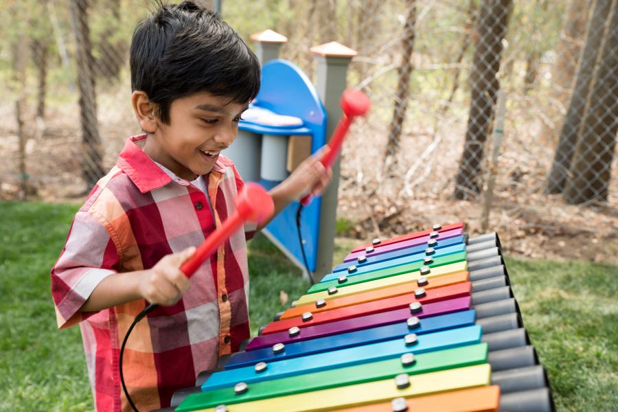 Boy playing xylophone in the Learn & Play Children's Garden
