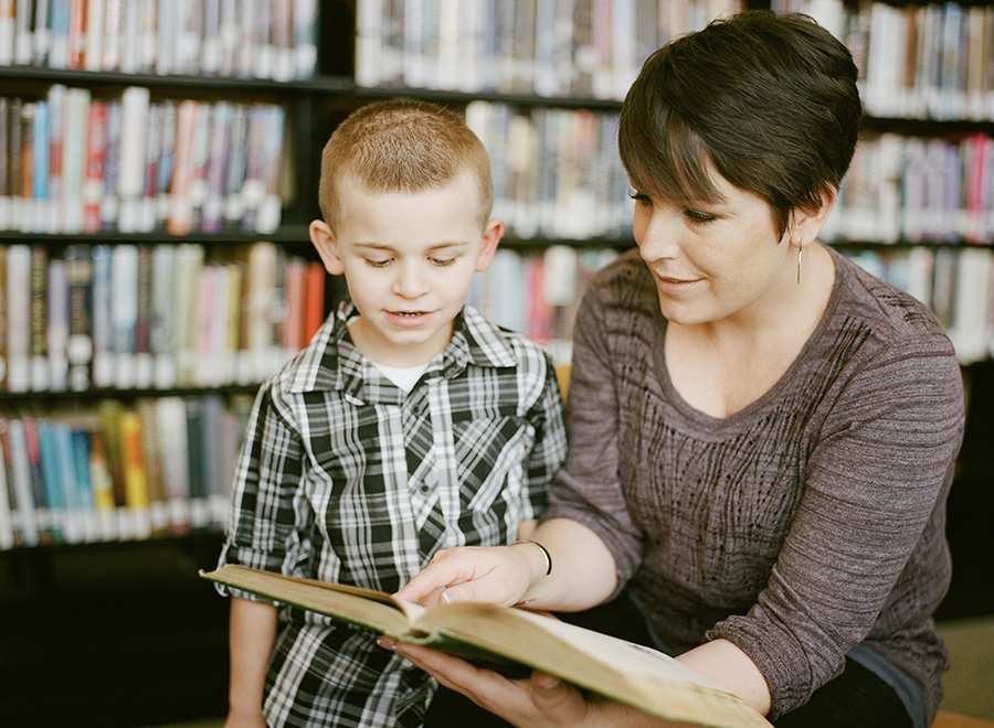 Parent and son looking at book together in library