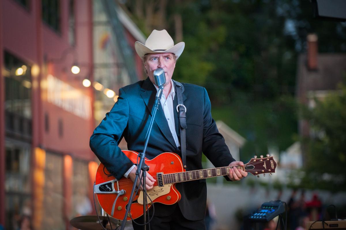 Gene Casey playing guitar at a street fair